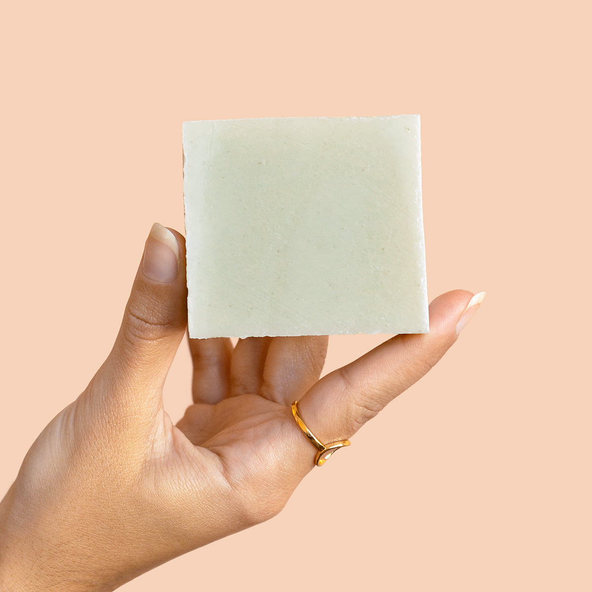 Hand holding a green BKIND Herbal body soap bar
