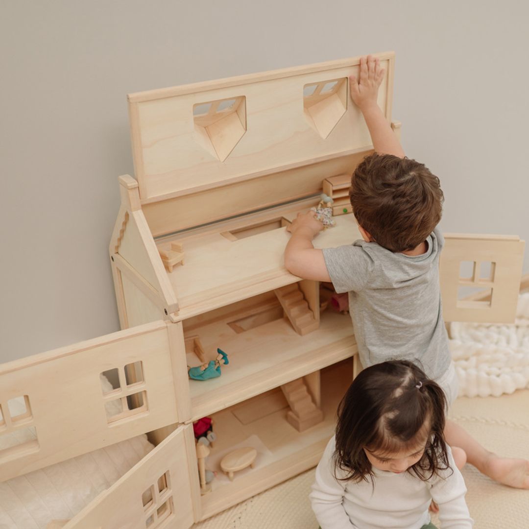 Children playing with the wooden PlanToys Victorian dollhouse
